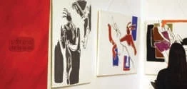 Artwork display in a gallery with a red panel and abstract paintings.