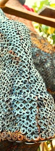 A close-up of metallic washer art, showing a textured, colorful surface.